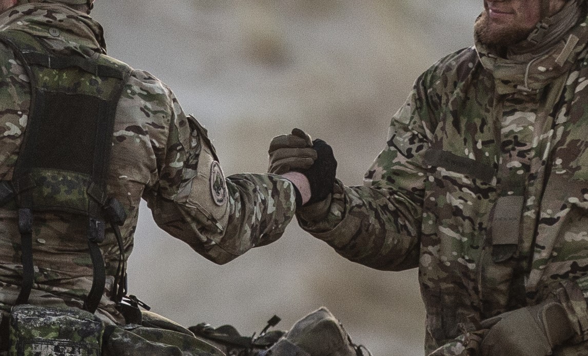 To soldater giver hinanden hånden som hjælp og anerkendelse