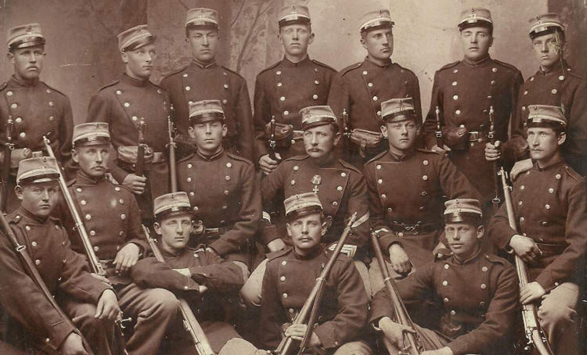 Gruppebillede fra 1880'erne af unge soldater i uniform og med geværer.