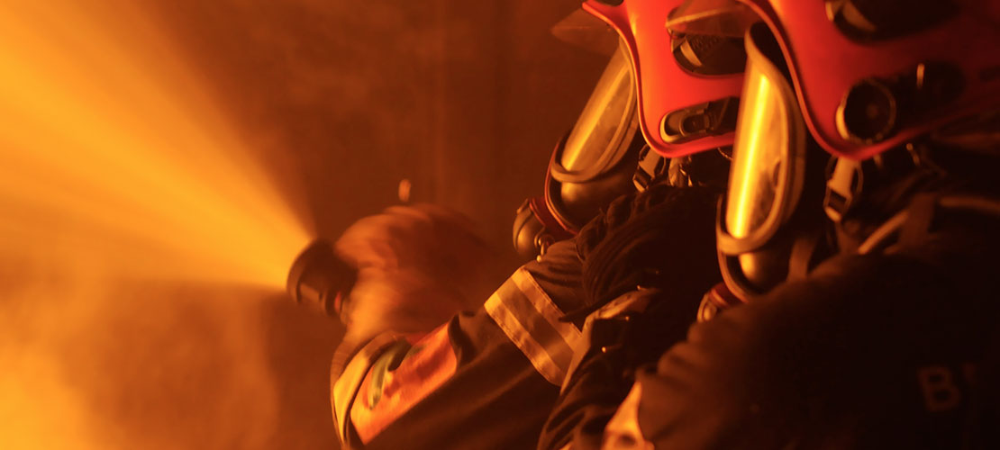 To personer i brandmandsuniform slukker en ild
