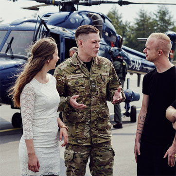 En ung kvinde i samtale med en soldat og to andre mænd foran en helikopter