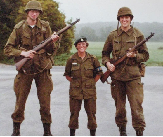 Dorte som er ca. 1,6 meter høj står flankeret af to høje kolleger. De bærer alle uniform og de to kolleger bærer våben.